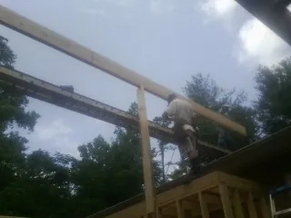 Carpenter setting a ridge beam over a new addition frame — Ice Dam Removal by Roofing Brothers in Hankins