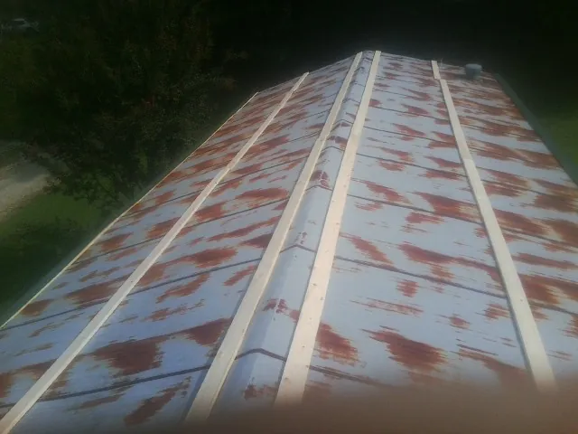 Rusted metal roof panels with new wood purlins before replacement — Storm Damage Roof Repair in Hankins by Roofing Brothers