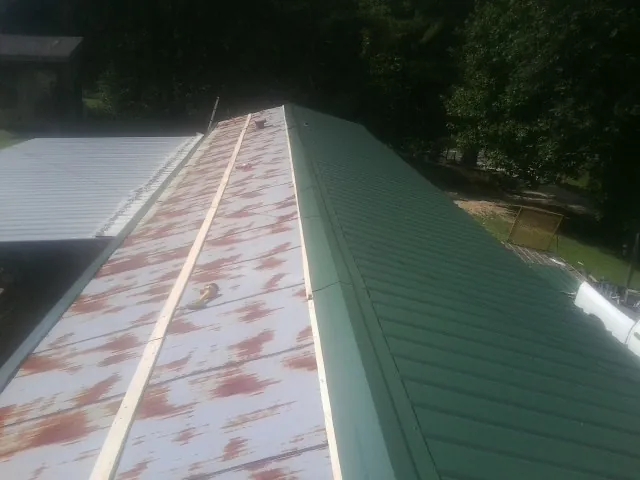 Old rusted panels beside newly installed green metal roofing — Wind Damage Roof Repair by Roofing Brothers in Hankins