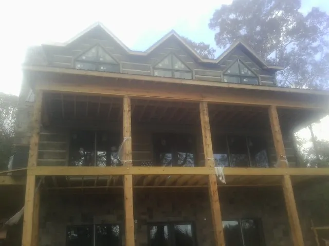 Dormers and porch framing on a large log home under construction — Roof Coating work by our crew in Hankins