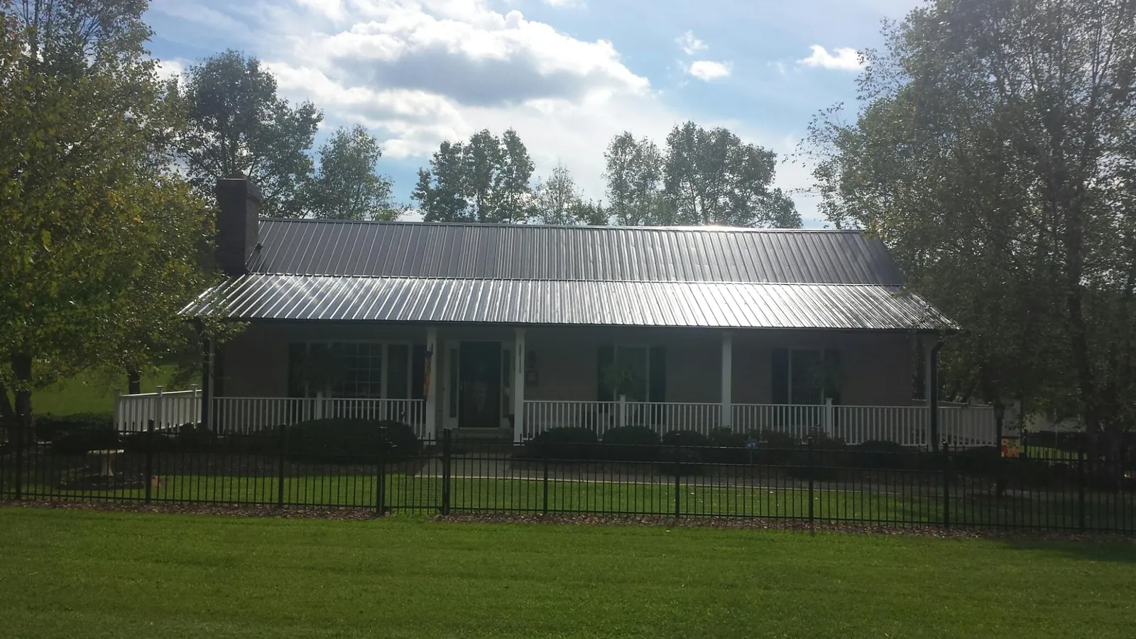 Gray metal roof on a brick ranch with a full width front porch — Gutter Guard Installation work by our crew in Hankins