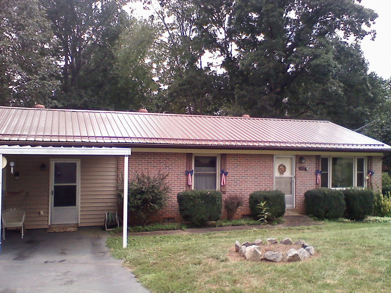 Bronze metal roof and carport on a brick ranch home — Roof Repair work by our crew in Hankins