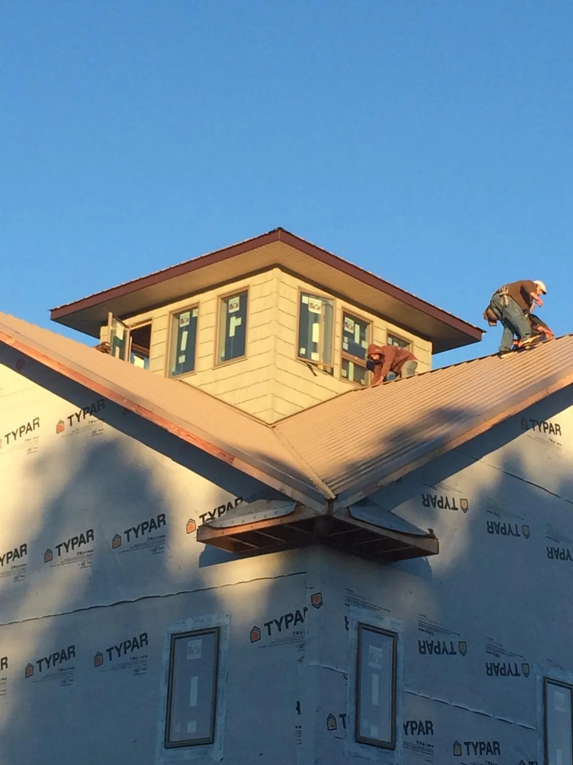 Roofers working around a rooftop cupola on a new metal roof at sunset — Roof Waterproofing in Hankins by Roofing Brothers
